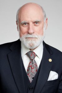 Vint Cerf headshot with blue suit, red and grey paisley tie and white shirt and pocket square